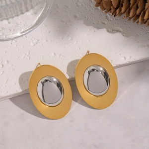Macro detail of geometric oval earrings featuring matte gold and shiny silver finish