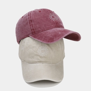 Détail de casquettes en coton délavé rouge et kaki avec broderie de tournesol