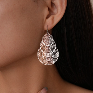 Vue détaillée de boucles d'oreilles pendantes à fleurs creuses portées par un mannequin