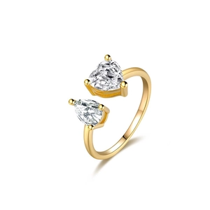 Detail of gold open ring featuring heart and teardrop shaped zircon stones on white background