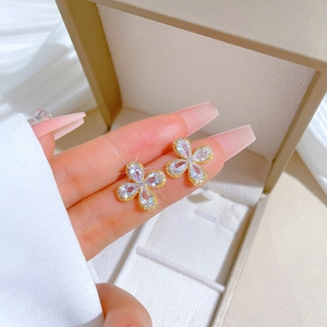 Elegant gold clover stud earrings with clear zircons and beaded edges on a jewelry box