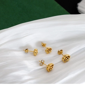 Detailed shot of four gold-tone 3D rose flower vintage studs on white silk fabric
