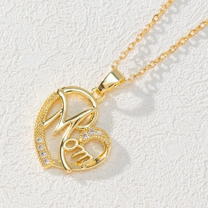 Close-up of heart-shaped gold necklace pendant with Mom lettering and zircon stones
