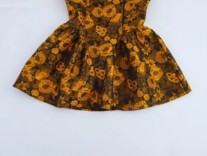 Detail of vintage jacquard mini dress with gold floral patterns and pleated A-line hem