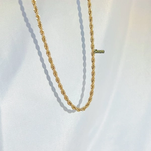 Close-up of 5mm gold chunky rope chain necklace draped on elegant white silk fabric