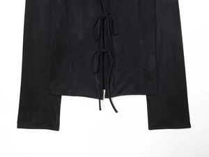 Détail d'un chemisier noir à manches longues avec liens noués et texture aspect suédine