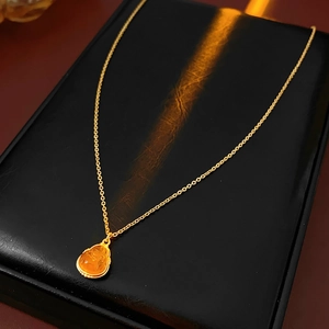 Detail of gold plated Buddha pendant necklace showing amber texture on black stand