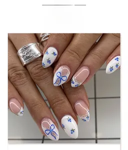 Detailed view of almond-shaped fake nails with blue bow and floral lace designs