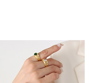 Detail of two-piece gold ring set with spiral texture, green and clear gemstones