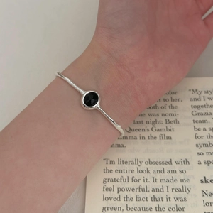 Minimalist S925 sterling silver open bangle with oval black onyx on a vintage book