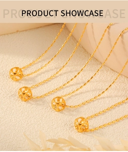 Close-up of four gold cube necklaces with bead chains on a textured white surface
