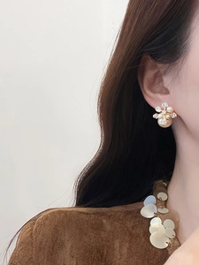 Gros plan de boucles d'oreilles fleurs avec perles et zircons sur le profil d'un modèle