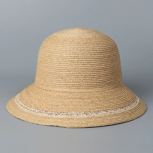 Detail of raffia sun hat featuring fine weave texture and white crochet lace trim