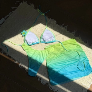 Détail d'un ensemble bikini dégradé avec paréo assorti posé sur un tapis texturé