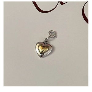 Detail shot of a two-tone S925 sterling silver heart pendant with golden accent and clasp