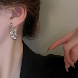 Close-up of silver tassel earrings with zircon leaf pendants on a female model