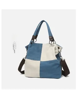 Close-up of blue and white canvas tote bag with brown leather handles and side chain