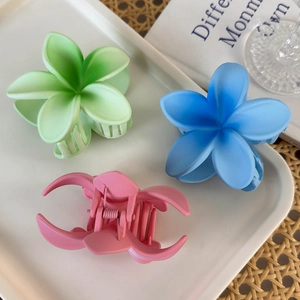Detailed view of floral hair claws in pastel pink, blue, and green on a white tray