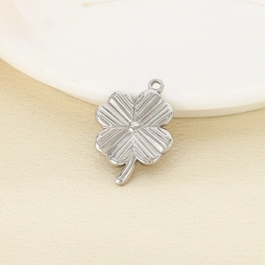 Macro shot of silver four-leaf clover pendant with radial texture on a ceramic dish