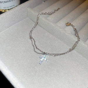 Detailed macro view of a silver double-layered cross bracelet with cubic zirconia