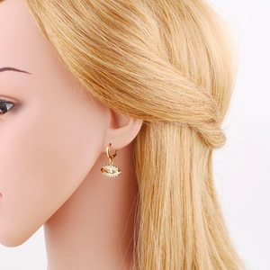 Close-up of golden Evil Eye drop earring with white zircon inlay on model's ear
