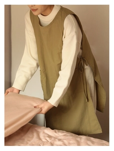 Olive green cotton linen apron with side ties used in a cozy home laundry setting
