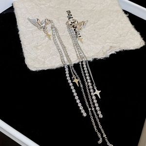 Close-up of silver tassel earrings featuring sparkling diamond wings and star pendants