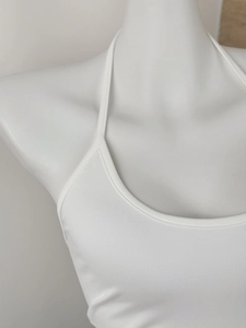Detailed close-up of a white knit halter top showing fine texture and sleek backless design