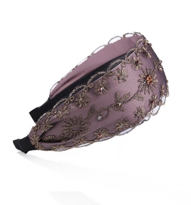 Primer plano de diadema ancha morada con bordados dorados y detalles de cuentas