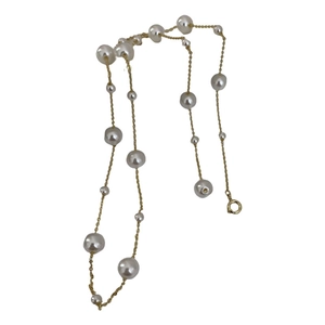 Minimalist gold necklace with geometric pearls in various sizes on a white background