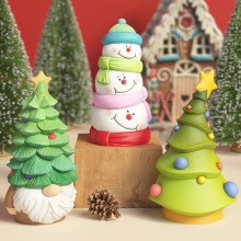 Three colorful resin Christmas figurines including a snowman and gnome on a festive table