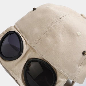 Khaki aviator style baseball cap with black goggles on a plain white background
