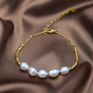Detail of 925 sterling silver gold bracelet with five pearls on brown silk backdrop