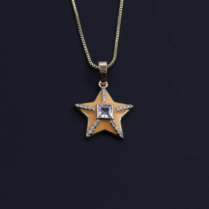 Detail shot of a 18k gold plated star pendant with orange enamel and zircon stones