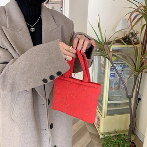 Close-up of red quilted puffer handbag with white contrast stitching and soft texture
