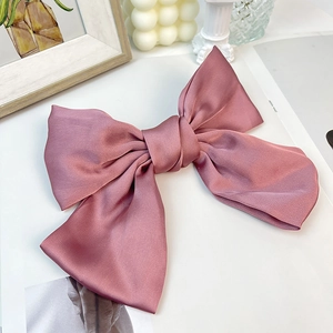 Detail view of the elegant dusty pink satin bow hair clip with smooth silky texture
