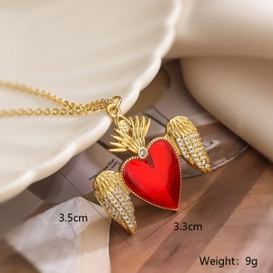 Detailed view of gold plated winged heart necklace with red enamel and white rhinestones