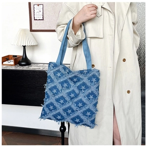 Detail of denim tote bag featuring frayed star patterns and large storage capacity