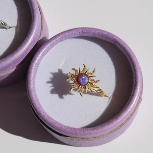 Macro shot of sunburst gold ring with purple opal center in a velvet jewelry box