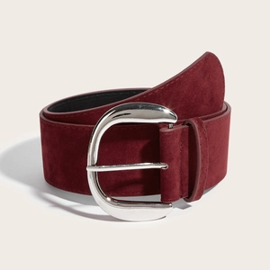 Close-up of a wide burgundy suede belt with a polished silver metallic horseshoe buckle