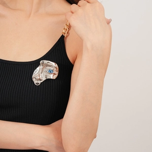 Artistic abstract silver face brooch with blue eye gemstone on black tank top