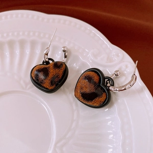 Close-up of leopard print heart earrings on a vintage white embossed porcelain plate