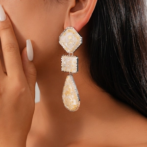 Gros plan de boucles d'oreilles géométriques en résine à trois niveaux sur un modèle