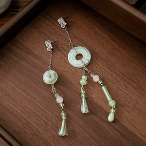 Macro detail of Chinese style tassel earrings with jade-like beads and silver chains
