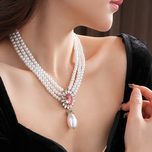 Gros plan du collier de perles multicouches avec un pendentif fleur serti de diamants roses