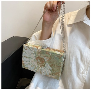 Close-up of floral brocade box clutch with silver chain strap and metal buckle