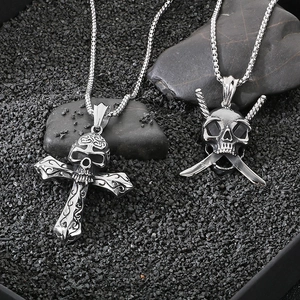 Detailed view of silver gothic skull and cross pendants on dark gravel background