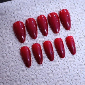 Glossy deep wine red almond shaped press-on nails set on white textured background