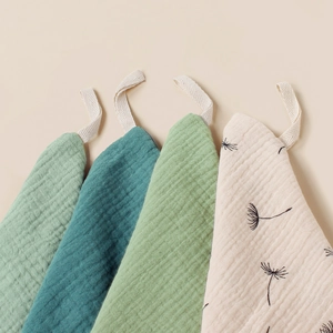 Detail of 4-pack muslin cotton baby washcloths featuring solid colors and dandelion print
