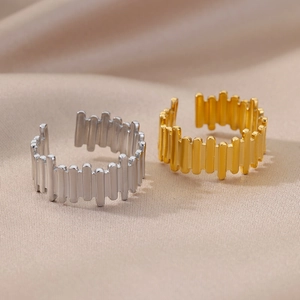 Detail of adjustable geometric 18k gold and silver rings on elegant rippled fabric